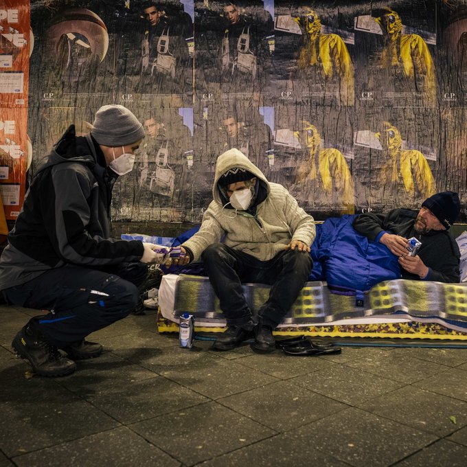 Ein Sozialarbeiter reicht einem Obdachlosen Suppe